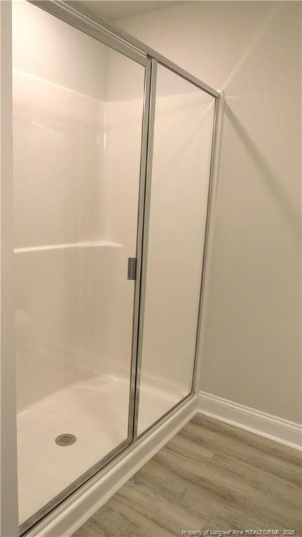 bathroom featuring wood-type flooring and a shower with shower door