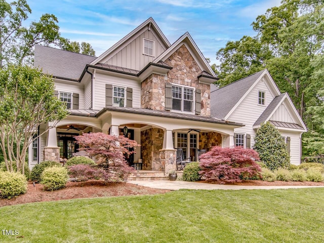 craftsman inspired home featuring metal roof, a standing seam roof, a porch, board and batten siding, and a front yard