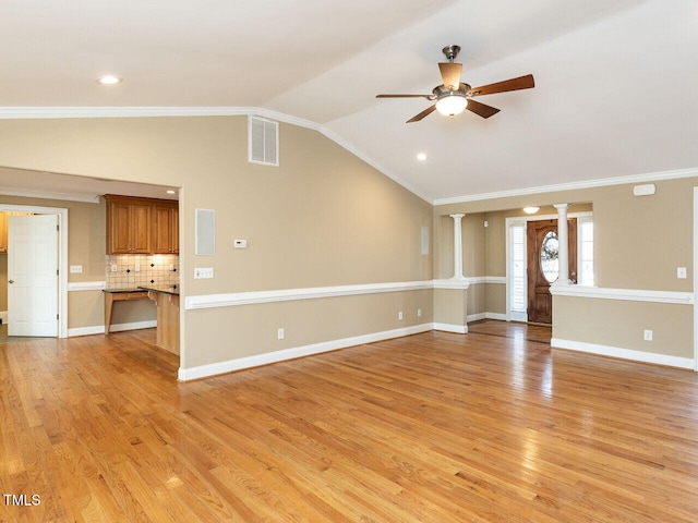 unfurnished living room featuring ornamental molding, vaulted ceiling, light hardwood / wood-style floors, and ornate columns