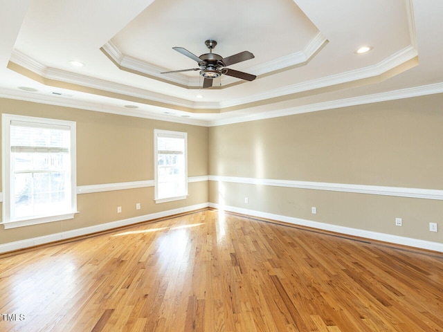 spare room with crown molding, ceiling fan, light hardwood / wood-style floors, and a tray ceiling