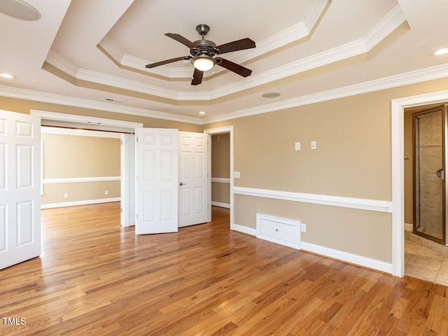 unfurnished room with a raised ceiling, crown molding, and light hardwood / wood-style flooring