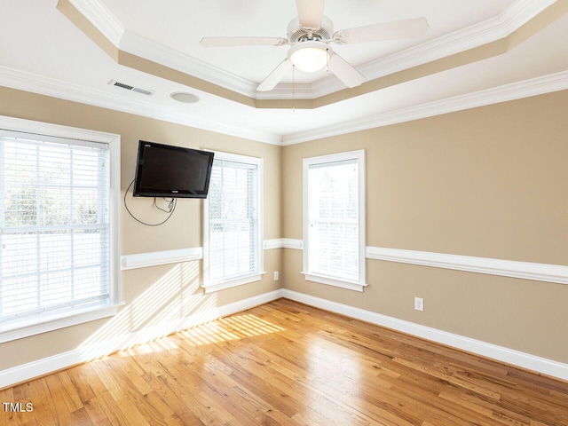 unfurnished room with light hardwood / wood-style flooring, ornamental molding, a raised ceiling, and ceiling fan