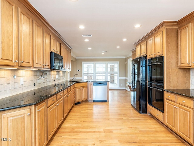 kitchen with black appliances, sink, dark stone counters, kitchen peninsula, and light wood-type flooring