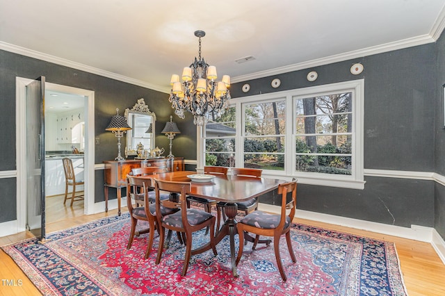 dining space featuring crown molding, wood-type flooring, and a chandelier