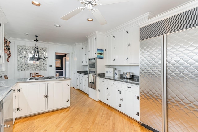 kitchen with decorative light fixtures, ornamental molding, stainless steel appliances, and white cabinets