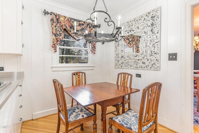 dining area with ornamental molding and light hardwood / wood-style floors