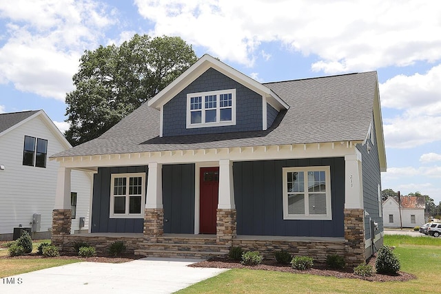 view of front of property featuring covered porch, a front yard, and central air condition unit