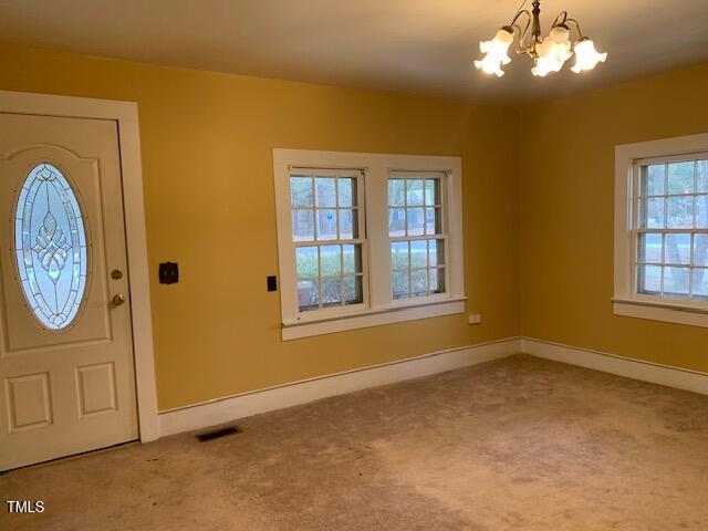 carpeted entryway featuring an inviting chandelier