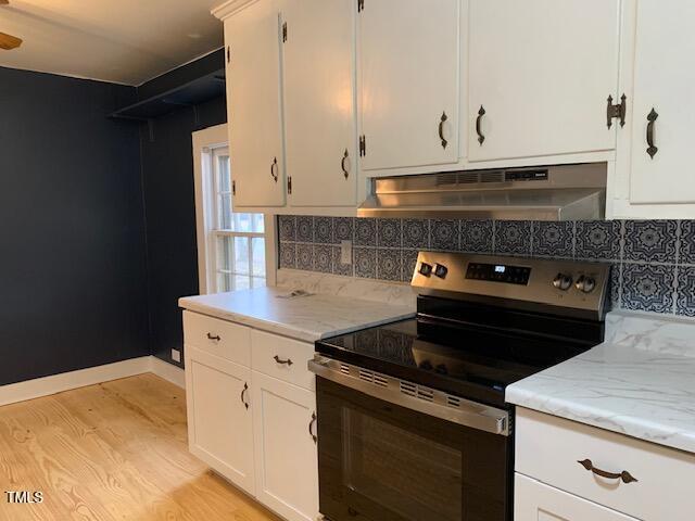 kitchen featuring decorative backsplash, white cabinets, light wood-type flooring, and stainless steel range with electric stovetop