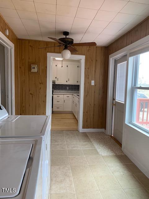 clothes washing area featuring ceiling fan, wooden walls, and independent washer and dryer