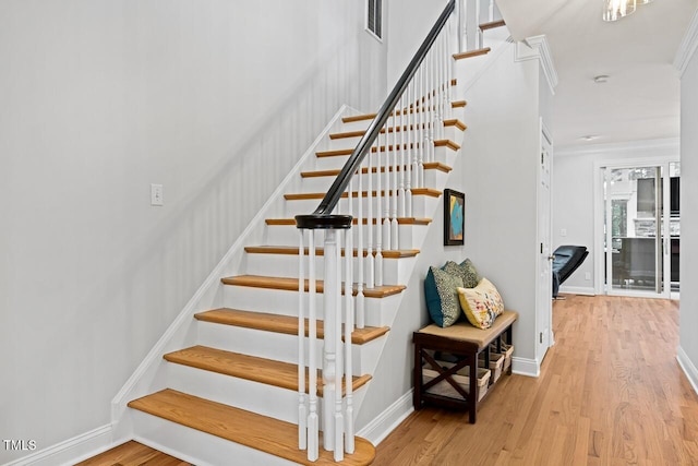 stairway with hardwood / wood-style flooring and ornamental molding