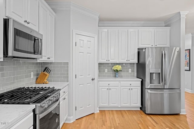 kitchen featuring backsplash, stainless steel appliances, white cabinets, and light wood-type flooring