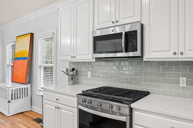 kitchen featuring crown molding, light stone counters, tasteful backsplash, stainless steel appliances, and white cabinets