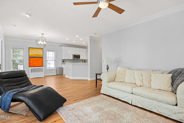 living room featuring crown molding, radiator, ceiling fan with notable chandelier, and light hardwood / wood-style floors