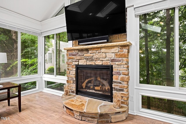 sunroom with lofted ceiling and a stone fireplace