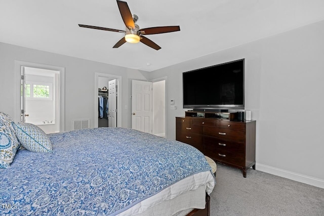 carpeted bedroom featuring a walk in closet and ceiling fan