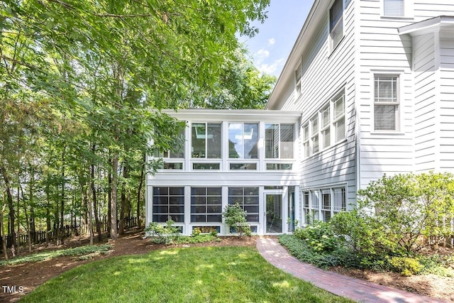 rear view of house with a yard and a sunroom