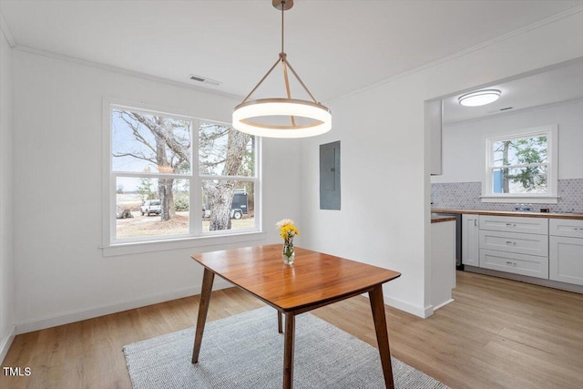 dining area featuring ornamental molding, electric panel, and light wood-type flooring