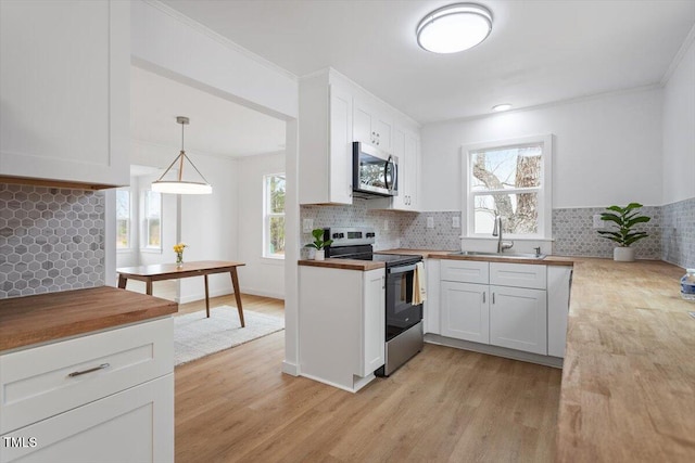 kitchen featuring stainless steel appliances, sink, pendant lighting, and white cabinets