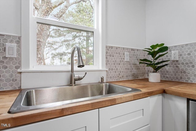 kitchen featuring white cabinetry, butcher block counters, sink, and tasteful backsplash