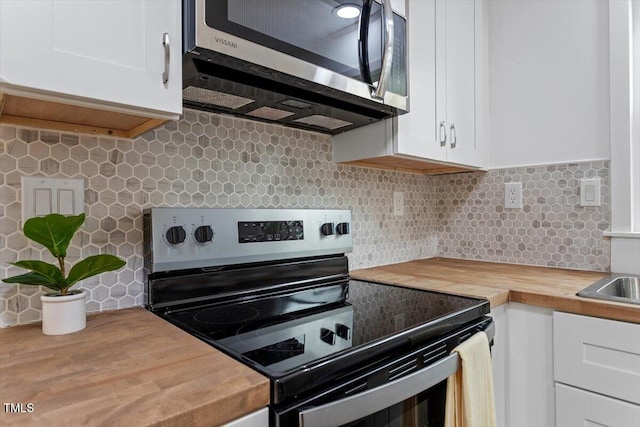 kitchen with stainless steel appliances, white cabinetry, and wood counters