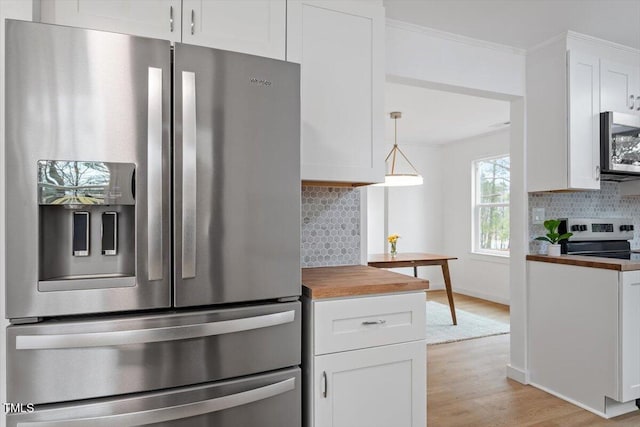 kitchen with crown molding, appliances with stainless steel finishes, white cabinets, wood counters, and decorative light fixtures