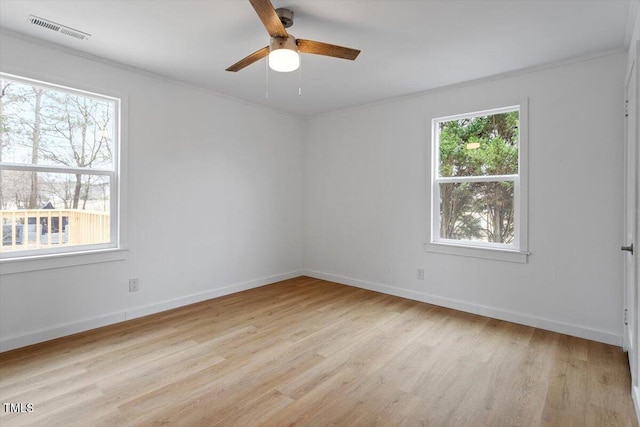 spare room with ornamental molding, a wealth of natural light, and light hardwood / wood-style floors