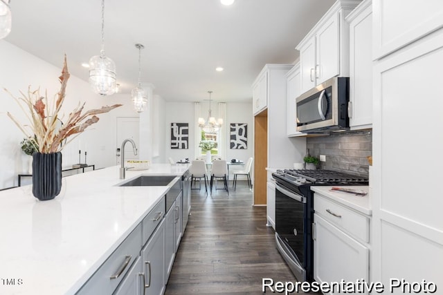 kitchen with decorative light fixtures, white cabinetry, sink, backsplash, and stainless steel appliances