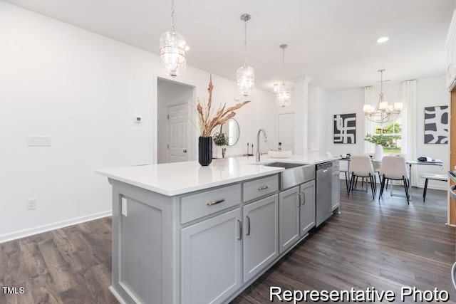 kitchen featuring pendant lighting, sink, gray cabinets, dishwasher, and an island with sink