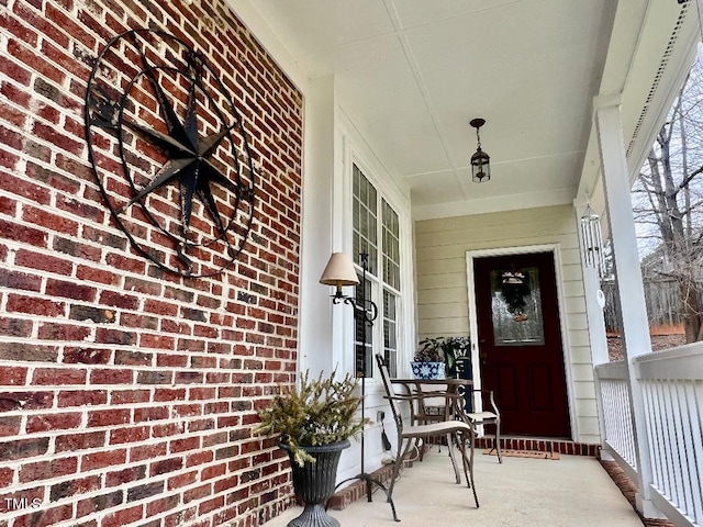 doorway to property featuring brick siding and covered porch