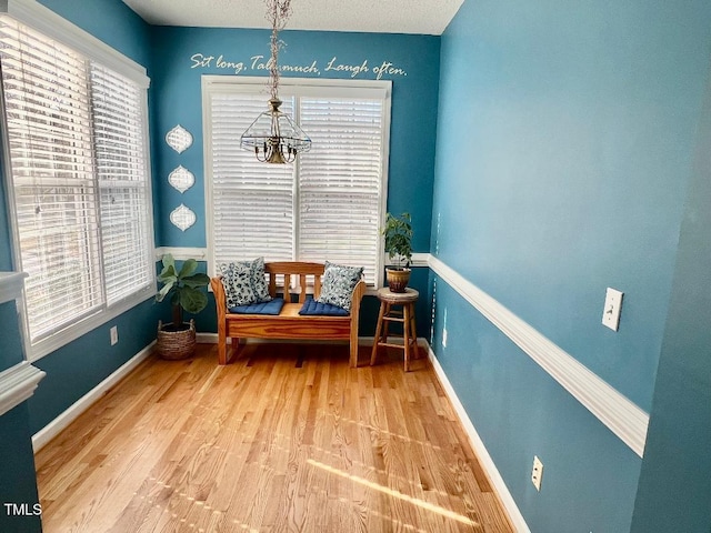 living area with a chandelier, wood finished floors, and baseboards