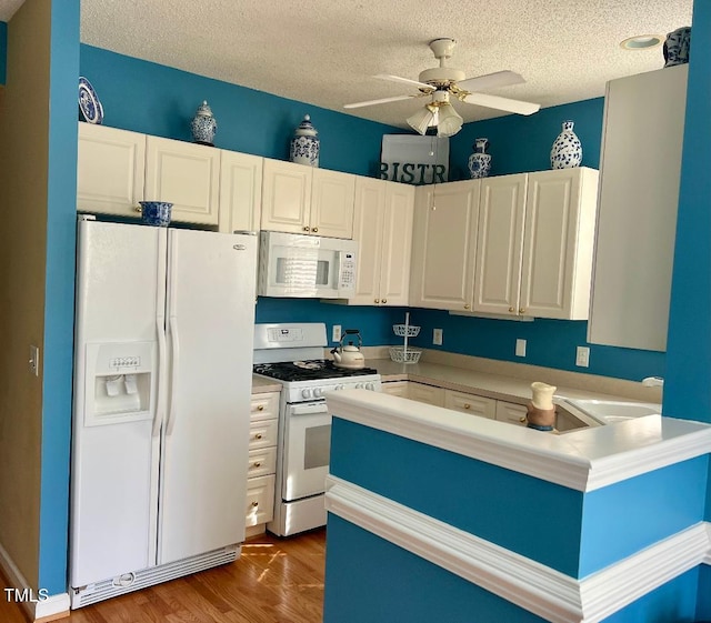 kitchen featuring white cabinetry, ceiling fan, a textured ceiling, wood finished floors, and white appliances