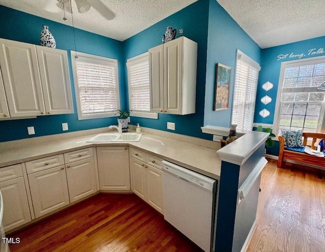 kitchen with dark wood-style flooring, white dishwasher, a sink, and white cabinets