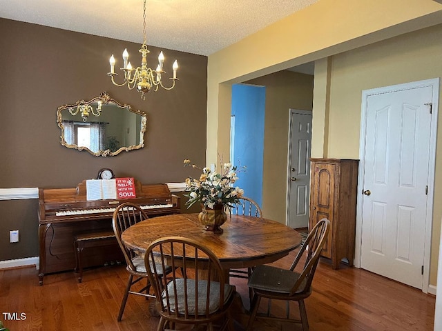 dining space with vaulted ceiling, a textured ceiling, wood finished floors, a chandelier, and baseboards