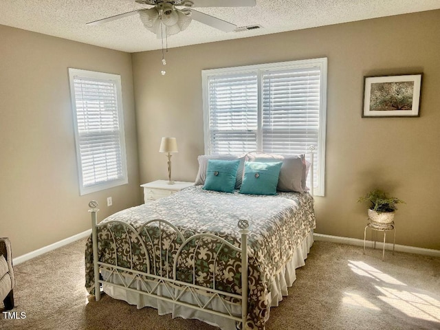 bedroom with a textured ceiling, a ceiling fan, visible vents, and baseboards