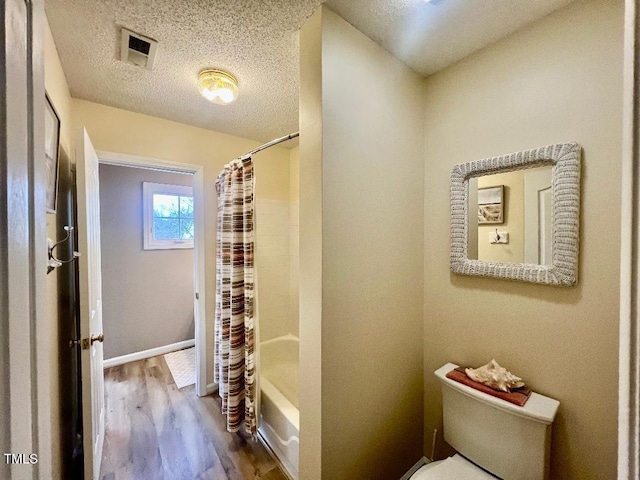 full bath with a textured ceiling, toilet, wood finished floors, visible vents, and shower / bath combo