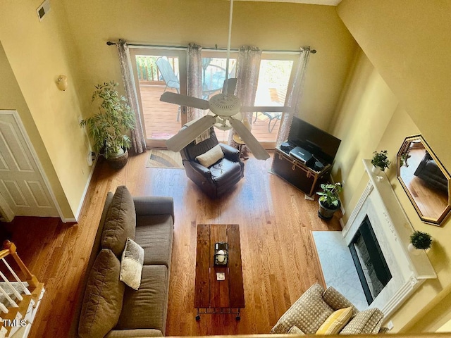 living area with a premium fireplace, wood finished floors, visible vents, and a healthy amount of sunlight