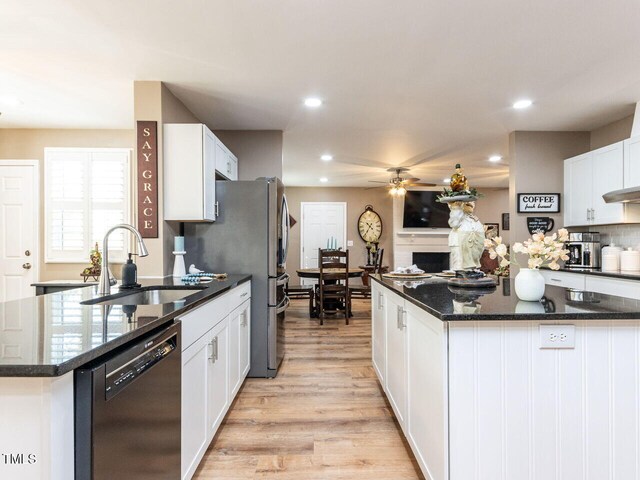 kitchen with light wood-type flooring, white cabinetry, a sink, and dishwashing machine
