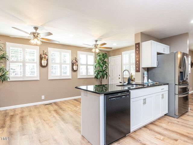 kitchen with a sink, baseboards, dishwasher, dark countertops, and stainless steel fridge