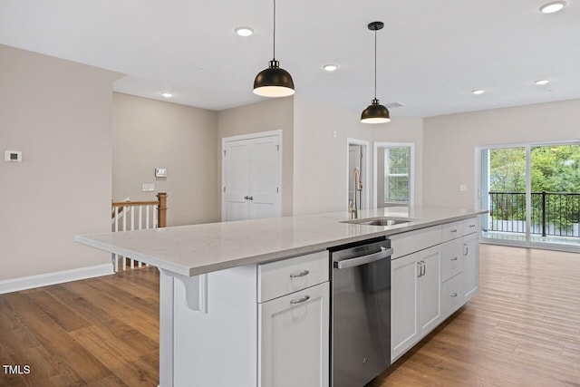 kitchen with pendant lighting, dishwasher, an island with sink, sink, and white cabinets