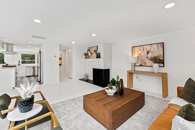 living room featuring a brick fireplace and sink