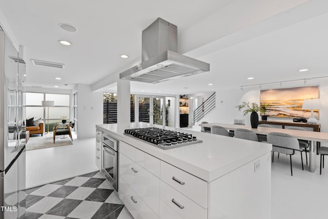 kitchen featuring white cabinetry, appliances with stainless steel finishes, island range hood, and a kitchen island