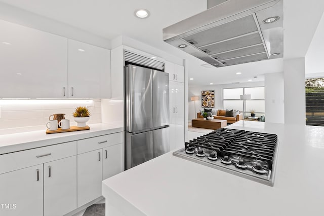 kitchen with stainless steel appliances, white cabinetry, backsplash, and wall chimney exhaust hood