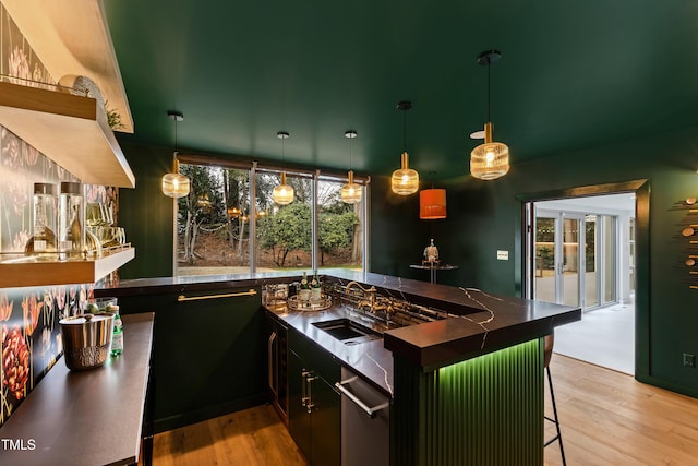 kitchen with sink, decorative light fixtures, a breakfast bar, and light wood-type flooring