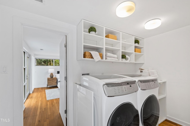 washroom with hardwood / wood-style floors and washing machine and clothes dryer