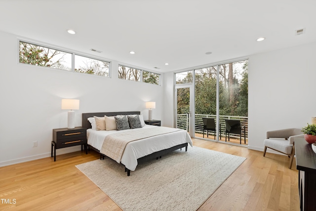 bedroom with access to exterior, light hardwood / wood-style flooring, and expansive windows