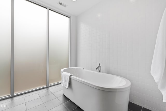 bathroom with tile walls, tile patterned floors, and a bathing tub