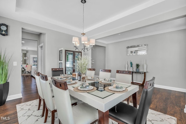 dining area featuring a chandelier, a tray ceiling, baseboards, and wood finished floors