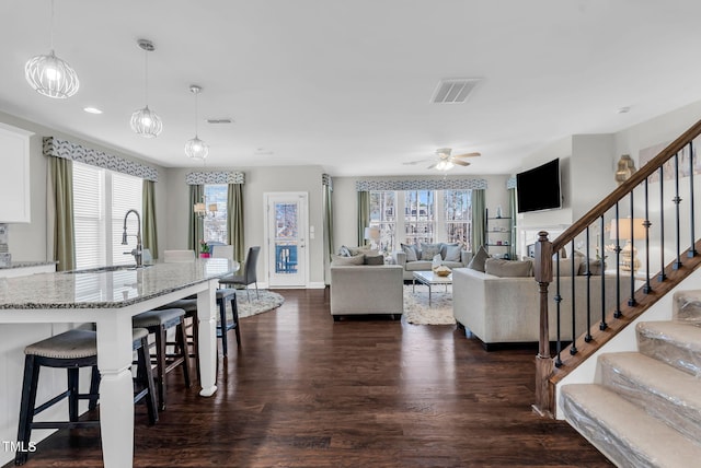 living area with dark wood-type flooring, visible vents, plenty of natural light, and stairway