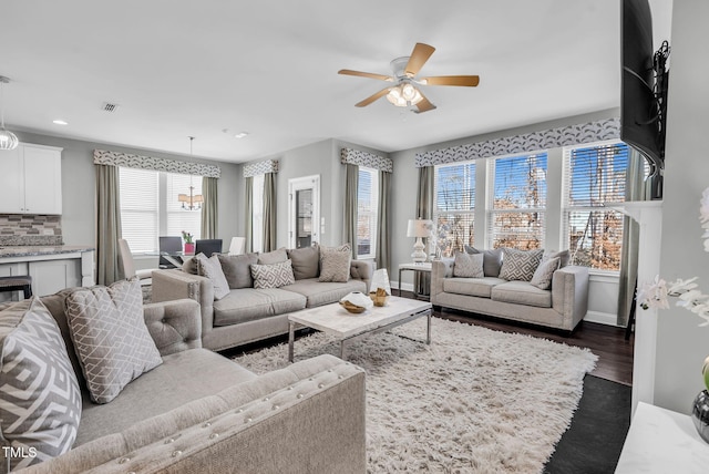 living area featuring baseboards, dark wood-type flooring, visible vents, and a ceiling fan